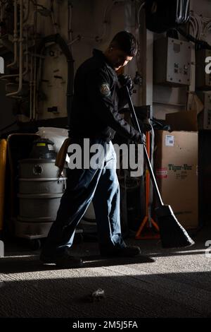 220318-N-VS068-1094 PAZIFIK (18. März 2022) – Aviation Boatswain’s Mate (Handling) Airman Diego Chavez kehrt das Hangar Bay Deck an Bord des Amphibienschiffs USS Makin Island (LHD 8), März 18. Makin Island führt Routineeinsätze in der US-3.-Flotte durch. Stockfoto