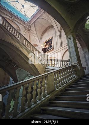 Louvre Palast architektonische Details einer Halle mit Steintreppe, kunstvoll verzierten Geländern und glühenden alten Lampen, Paris, Frankreich Stockfoto