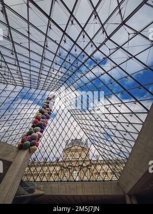 Unter der Glaspyramide des Louvre, vertikaler Hintergrund. Wunderschöne architektonische Details mit einer abstrakten Mischung aus klassischem und modernem Stil Stockfoto