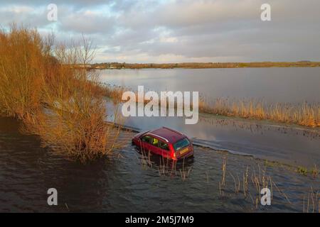 Muchelney Somerset, Großbritannien. 29. Dezember 2022 Wetter in Großbritannien. Ein Auto steckt auf der Straße zwischen Muchelney und Langport in Somerset in Überschwemmungen fest, nachdem die Flussparrett ihre Ufer geplatzt und die Felder und die Straße nach starkem Regen überflutet hat. Bildnachweis: Graham Hunt/Alamy Live News Stockfoto