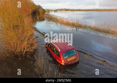 Muchelney Somerset, Großbritannien. 29. Dezember 2022 Wetter in Großbritannien. Ein Auto steckt auf der Straße zwischen Muchelney und Langport in Somerset in Überschwemmungen fest, nachdem die Flussparrett ihre Ufer geplatzt und die Felder und die Straße nach starkem Regen überflutet hat. Bildnachweis: Graham Hunt/Alamy Live News Stockfoto