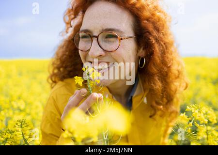 Junge Frau, die eine schöne Blume riecht Stockfoto