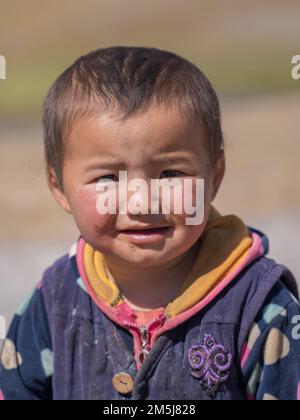 Achik Tash, Kirgisistan - 08 29 2019 : Nahaufnahme des kirgisischen kleinen Jungen, das auf das Lenin Peak Basislager blickt und lächelt Stockfoto