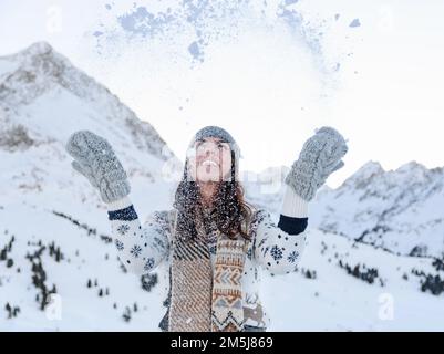 Eine Frau mit Winterhandschuhen, die im Skigebiet Kuhtai in Otztal, Österreich, mit Schnee spielt Stockfoto