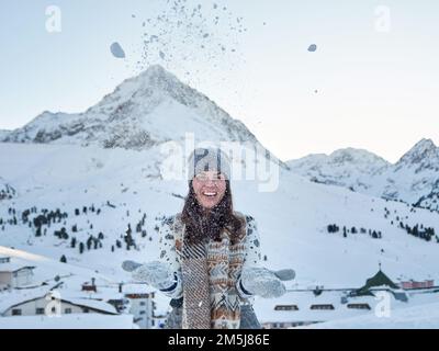 Eine Frau mit Winterhandschuhen, die im Skigebiet Kuhtai in Otztal, Österreich, mit Schnee spielt Stockfoto