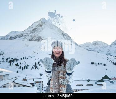 Eine Frau mit Winterhandschuhen, die im Skigebiet Kuhtai in Otztal, Österreich, mit Schnee spielt Stockfoto