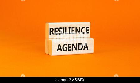 Symbol für Resilienz-Agenda. Konzeptwort „Resilience Agenda“ auf Holzblöcken getippt. Schöner orangefarbener Tischhintergrund. Unternehmen und Widerstandsfähigkeit Stockfoto