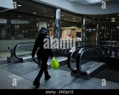 Eine Frau mit einer Handtasche geht zu den Rolltreppen auf der überdachten Bagration Bridge. Moskau, Russland. Stockfoto