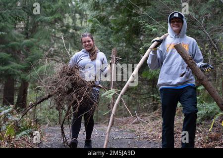 KITSAP COUNTY, Washington (18. März 2022) – USA Navy Aviation Electronics Technician 2. Class Mattison Underhill, aus Lake Tahoe, Kalifornien, links und USA Navy Aviation Maintenance Administrationman 3. Class Chase Reidinger aus Phoenix, dem Flugzeugträger der Nimitz-Klasse USS Theodore Roosevelt (CVN 71) zugeteilt, trägt Bromble während einer gemeinnützigen Veranstaltung am 18. März 2022 in den Müll. Theodore Roosevelt unterzieht sich einer geplanten zusätzlichen Anlegephase an der Puget Sound Naval Shipyard und der Intermediate Maintenance Facility, wo das Schiff planmäßig gewartet und modernisiert wird. Stockfoto