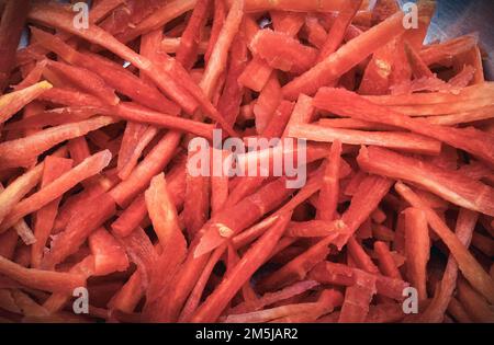 Geriebene Karotten in kleinen Stücken, ein Haufen frischer roter geriebener Karotten, eine Schnittkollage und geriebene Karotten auf Holz Stockfoto