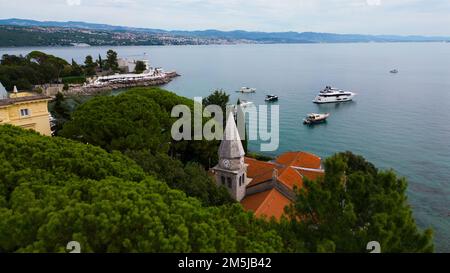 Aus der Vogelperspektive auf St. Jakobskirche, versteckt in Bäumen vor der Meereslandschaft in Opatija Stockfoto