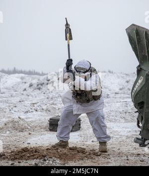 EIN US-AMERIKANISCHER Army Artilleryman mit Charlie Battery, 2. Bataillon, 8. Artillerie-Regiment, 1. Brigade-Kampfteam, 25. Infanteriedivision pulverisiert den eisigen Boden an der Schusslinie mit einer Spitzhacke, um den M777. Howitzer während des Joint Pacific Multinational Readiness Center 22-02 zu versenken. JPMRC 22-02 demonstriert die effektive Synergie zwischen widerstandsfähigen und gut ausgebildeten Soldaten, modernisierter und robuster Ausrüstung für kaltes Wetter und einzigartigen Taktiken, Techniken und Verfahren zur Bekämpfung der Letalität in arktischen Umgebungen. Stockfoto