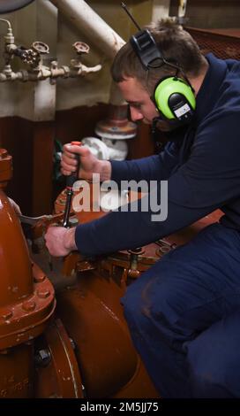 Coast Guard Petty Officer 3. Class Michael Covey, ein Maschinentechniker an Bord des Coast Guard Cutter Spar, verspannt die Oberseite der Seekiste nach der Reinigung der Siebe während der Fahrt im Atlantischen Ozean, 19. März 2022. Spar und ihre Crew reisen nach Duluth, Minn. nach einer einjährigen Wartungszeit in Baltimore. Stockfoto