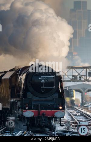 Dampfeisenbahn 46233 Duchess of Sutherland nähert sich Clapham Junction an einem eiskalten Dezembermorgen, mit Londoner Skyline im Hintergrund Stockfoto