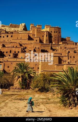 Marokko. Ksar d'Ait Ben Haddou im Atlasgebirge Marokkos. UNESCO-Weltkulturerbe seit 1987. Eine Frau, die vor dem Dorf spaziert Stockfoto