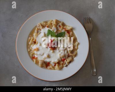 Bereit für traditionelle türkische mantı. Die berühmteste türkische Speisemanti auf dem Tisch. Handgemachte Mantelwahnsinnige. Türkische hausgemachte Knödel mit Hackfleisch und Zwiebeln Stockfoto