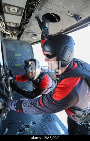 Sgt.1. Klasse Roger Ross (rechts) ein Fallschirmspringer mit dem Fallschirmteam des US Army Special Operations Command, den Black Daggers und Sgt. 1. Klasse Andrew Davis (links) steht auf den Gleitern eines MAG49-Hubschraubers vor einem Sprung an der Naval Air Station Joint Reserve Base New Orleans, 20. März 2022. Mitglieder des Teams eröffneten die New Orleans Air Show 2022 auf der Basis. Während des Abstiegs sprang das Team mit einer Sonderflagge zum 80. Jahrestag des 377. Theater Sustainment Command. Stockfoto