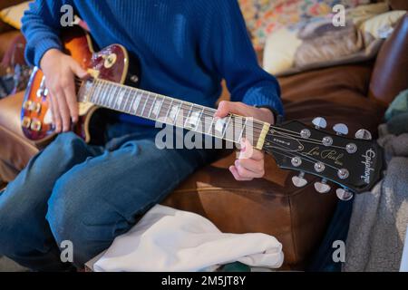 Ein männlicher Teenager, der eine E-Gitarre spielt, die er zu Weihnachten bekam - ein Gibson Les Paul Model Epiphone - ein Vintage-Modell. England Stockfoto