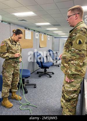 USA Army Staff Sergeant Cory Saxe, Right, gibt Anweisungen, wie man einen Schweizer Sitz an Sergeant Ashley Savage, Left, am 20. März 2022, während der Kampfversammlung in Fort Knox bindet. Ky. Die zwei nicht kommissionierten Offiziere von Kompanie B, 4. Bataillon, 399. Regiment, werden diesen Sommer als Rapelturmlehrer beim Cadet Summer Training dienen. Stockfoto