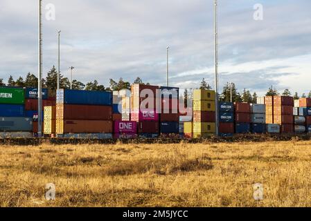 Burghausen, Deutschland - Dezember 29,2022: Frachtcontainer in einem Frachtbahnhof gestapelt, um auf Züge oder LKWs verladen zu werden. Stockfoto