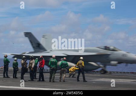 PHILIPPINISCHE SEE (21. März 2022) Seeleute beobachten den Flugbetrieb auf dem Cockpit des Flugzeugträgers der Nimitz-Klasse USS Abraham Lincoln (CVN 72). Die Abraham Lincoln Strike Group befindet sich in einem geplanten Einsatz im US-7.-Flottenbereich, um die Interoperabilität durch Allianzen und Partnerschaften zu verbessern und gleichzeitig als einsatzbereite Truppe zur Unterstützung einer freien und offenen Region Indo-Pacific zu fungieren. Stockfoto