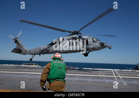 Ein MH-60s Nighthawk, der den „Tridents“ des Helicopter Sea Combat Squadron (HSC) 9 beigefügt ist, nähert sich dem Flugdeck von USS Gerald R. Ford (CVN 78), 21. März 2022. Ford führt im Atlantik im Rahmen der auf das Schiff zugeschnittenen Grundphase vor dem Einsatz die Zertifizierung des Cockpits und die Qualifikation von Luftfahrtunternehmen durch. Stockfoto