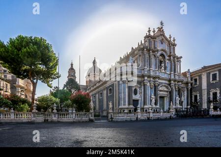 Basilika der Cattedrale di Sant'Agata mit blühenden Büschen: Weiß und rot im Garten neben =Sonnenaufgang am Morgen in der Innenstadt von Catania Stockfoto