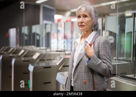 Reife Dame geht durch die Schranken in der U-Bahn-Station Stockfoto