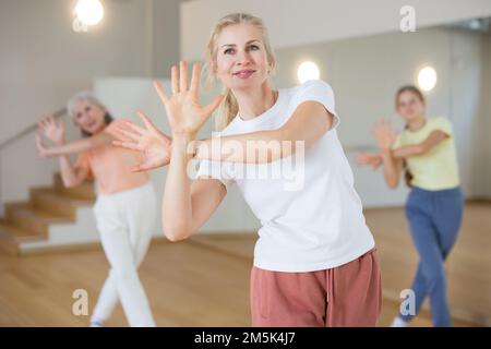 Frau tanzt modernen Tanz mit anderen Frauen während des Gruppentrainings im Klassenzimmer Stockfoto