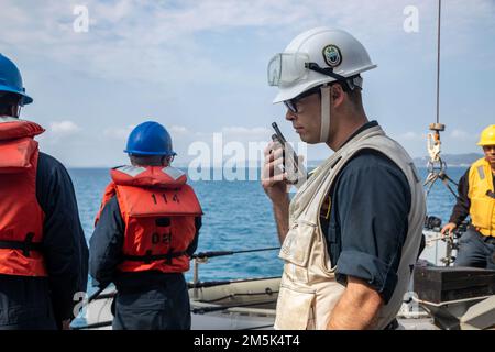 OKINAWA, Japan (21. März 2022) LT. j.g. Matthew Vick aus Van Buren, Maine, kommuniziert mit dem Pilotenhaus, während er an Bord der Arleigh-Burke-Klasse-Guided-Missile Destroyer USS Ralph Johnson (DDG 114) kleine Bootseinsätze durchführt. Ralph Johnson ist der Task Force 71/Destroyer Squadron (DESRON) 15, dem größten nach vorn verlegten DESRON der Marine, und der Hauptstreitkraft der US-7.-Flotte zugewiesen. Stockfoto