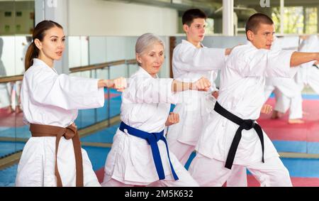 Leute in Kimonos üben Schläge während des Kampfsporttrainings Stockfoto