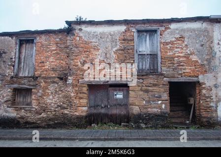 Eine Ruine im Angebot. Ein altes Bauernhaus im Dorf Tricastela auf dem Saint-James-Weg nach Santiago de Compostela mit einem Schild eines Immobilienmaklers. Stockfoto