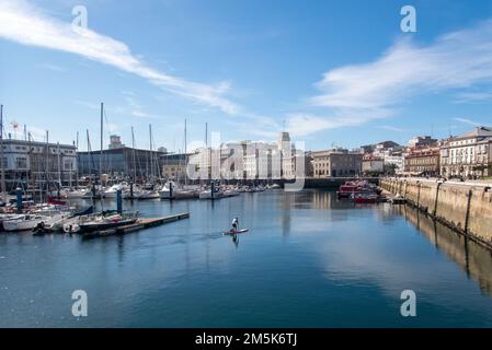 Stehen Sie auf und paddeln Sie in Einem Hafen von Coruña. Ein Mann und sein Hund genießen den Tag auf einem kleinen Brett. Stockfoto