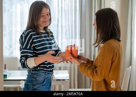 Zwei Mädchen feiern Feiertage und schenken einander Geschenke. Stockfoto