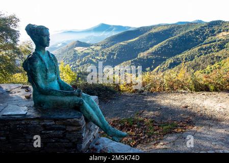 Der kleine Pilger. Statue einer jungen Frau, die mit einem Rucksack am Bergpass von O Cebreiro in Galicien, Nordspanien, entlang der historischen Pilgerroute des Camino de Santiago sitzt Stockfoto