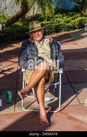 76-jähriger Sonnenbader, der an seinem Geburtstag auf einem Gartenstuhl auf dem De La Guerra Plaza in Santa Barbara, Kalifornien, saß. Stockfoto