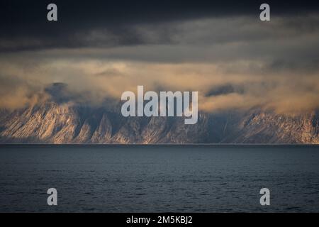 Die bergige Küste von Bylot Island in Nunavut, Kanada, ist teilweise von Wolken verdeckt. Stockfoto