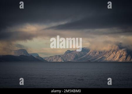 Die bergige Küste von Bylot Island in Nunavut, Kanada, ist teilweise von Wolken verdeckt. Stockfoto