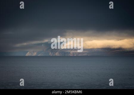 Die bergige Küste von Bylot Island in Nunavut, Kanada, ist teilweise von Wolken verdeckt. Stockfoto