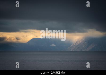 Die bergige Küste von Bylot Island in Nunavut, Kanada, ist teilweise von Wolken verdeckt. Stockfoto