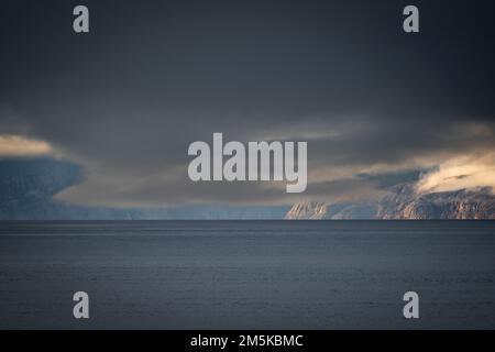 Die bergige Küste von Bylot Island in Nunavut, Kanada, ist teilweise von Wolken verdeckt. Stockfoto