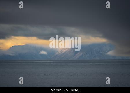 Die bergige Küste von Bylot Island in Nunavut, Kanada, ist teilweise von Wolken verdeckt. Stockfoto