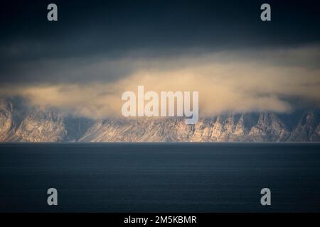 Die bergige Küste von Bylot Island in Nunavut, Kanada, ist teilweise von Wolken verdeckt. Stockfoto