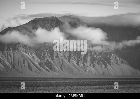 Die bergige Küste von Bylot Island in Nunavut, Kanada, ist teilweise von Wolken verdeckt. Stockfoto