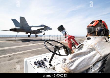 Aviation Boatswain's Mate (Handling) Airman Nathaniel Williams, aus Bay City, Michigan, der Luftabteilung von USS Gerald R. Ford (CVN 78) zugeteilt, mans ein P-25 Feuerwehrauto als F/A-18F Super Hornet, das an die „Blacklions“ des Strike Fighter Squadron (VFA) 213 angeschlossen ist, landet am 22. März 2022 auf dem Cockdeck. Ford führt im Atlantik im Rahmen der auf das Schiff zugeschnittenen Grundphase vor dem Einsatz die Zertifizierung des Cockpits und die Qualifizierung von Flugzeugflügelfluggesellschaften durch. Stockfoto