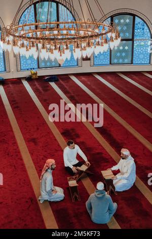 Eine Gruppe von Muslimen, die das heilige Buch des Korans während des muslimischen Feiertags von Ramadan in einer modernen Moschee las Stockfoto