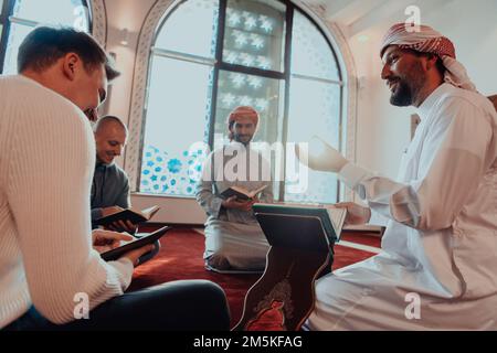 Eine Gruppe von Muslimen, die das heilige Buch des Korans während des muslimischen Feiertags von Ramadan in einer modernen Moschee las Stockfoto