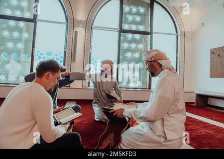 Eine Gruppe von Muslimen, die das heilige Buch des Korans während des muslimischen Feiertags von Ramadan in einer modernen Moschee las Stockfoto