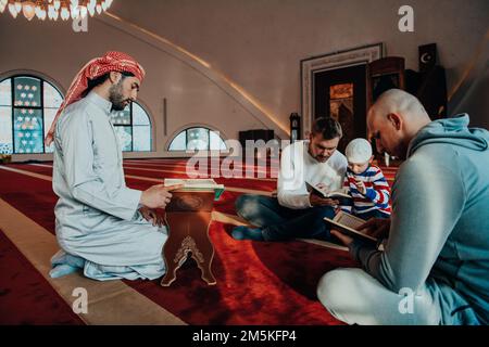 Eine Gruppe von Muslimen, die das heilige Buch des Korans während des muslimischen Feiertags von Ramadan in einer modernen Moschee las Stockfoto