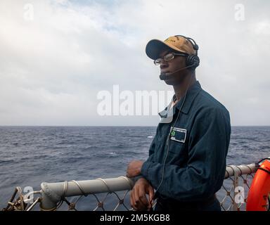 SÜDCHINESISCHES MEER (22. März 2022) Seemann Ifeoluwadayo Akinkugbe aus New Orleans, Louisiana, beobachtet auf dem Flugdeck an Bord des Arleigh-Burke-Klasse-Zerstörers USS Ralph Johnson (DDG 114). Ralph Johnson ist der Task Force 71/Destroyer Squadron (DESRON) 15, dem größten nach vorn verlegten DESRON der Marine, und der Hauptstreitkraft der US-7.-Flotte zugewiesen. Stockfoto